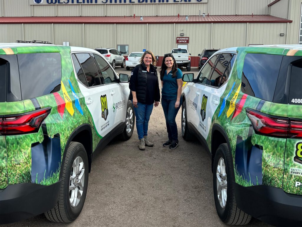Two women standing in front of vehicles